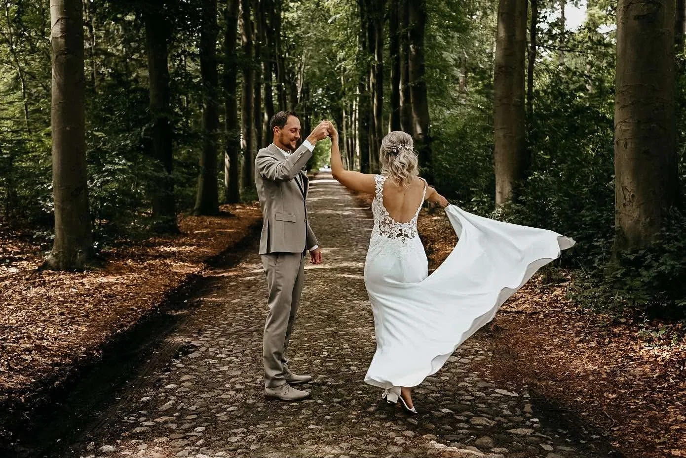 Bruid draait een pirouette met haar bruidegom op een bospad