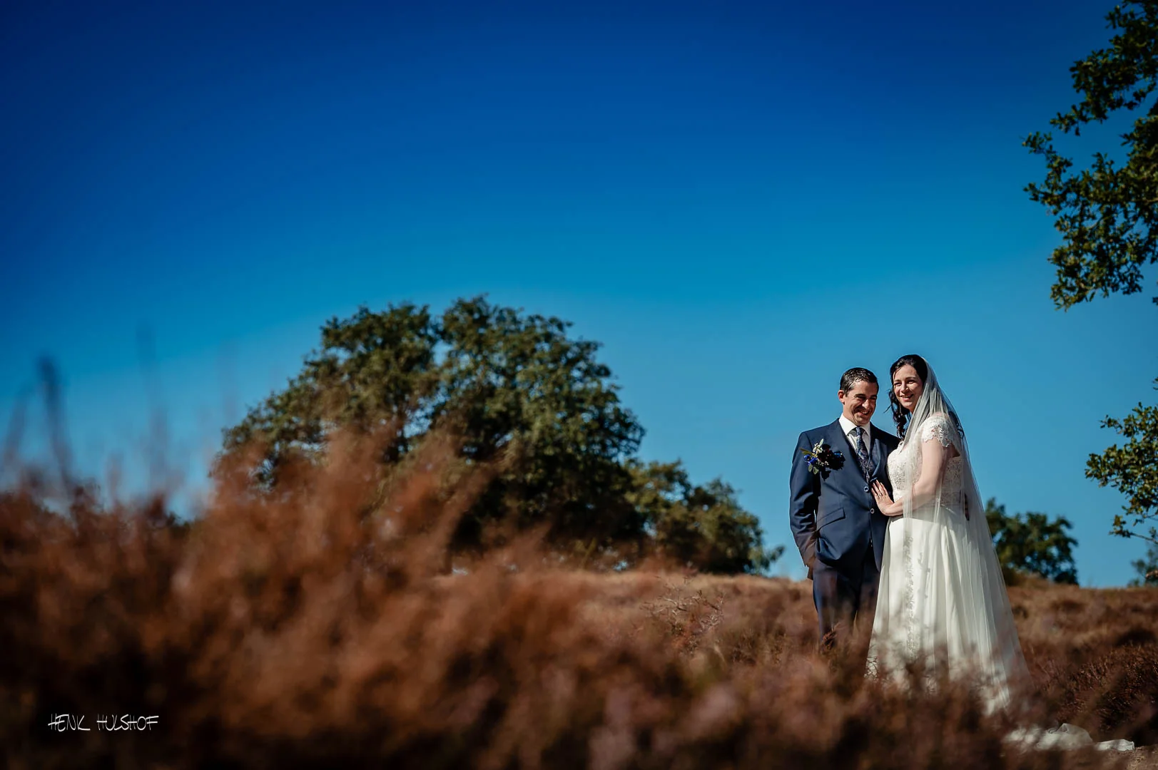 Bruidspaar op de heide onder een strakblauwe lucht