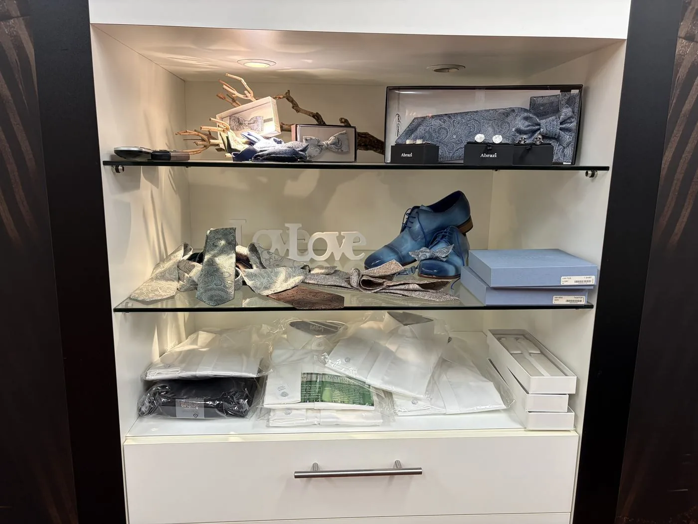 Vitrine met dassen, manchetknopen, schoenen en overhemden in de herenafdeling