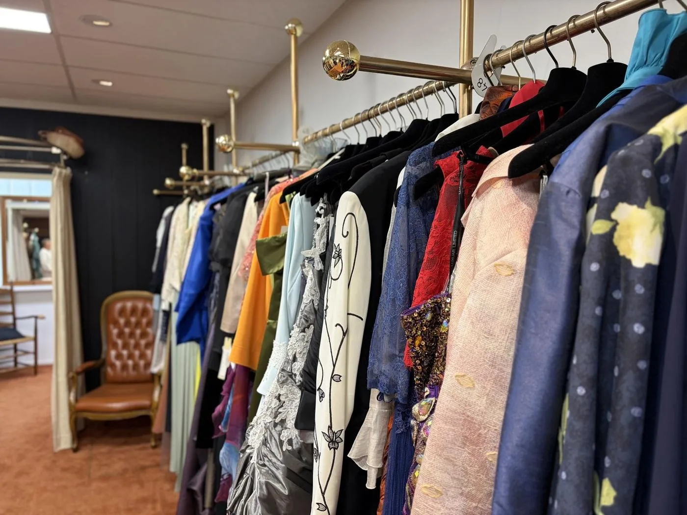 Gelegenheidskleding in veel kleuren aan een koperen rek