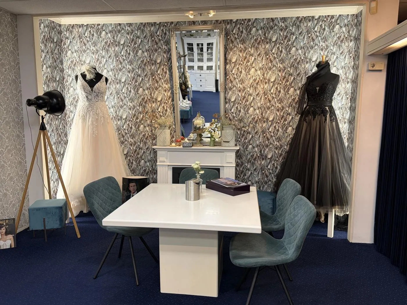 Tafel met stoelen tussen twee trouwjurken in de bruidssalon